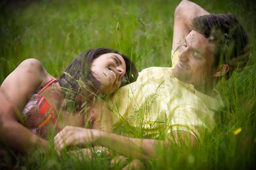 Engaged couple chatting while they lie in a tall grass meadow at Knole Park