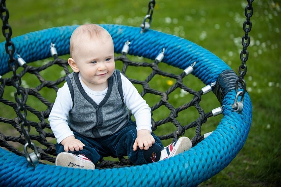 Baby sits on a rope swing at a Kemsing Playground