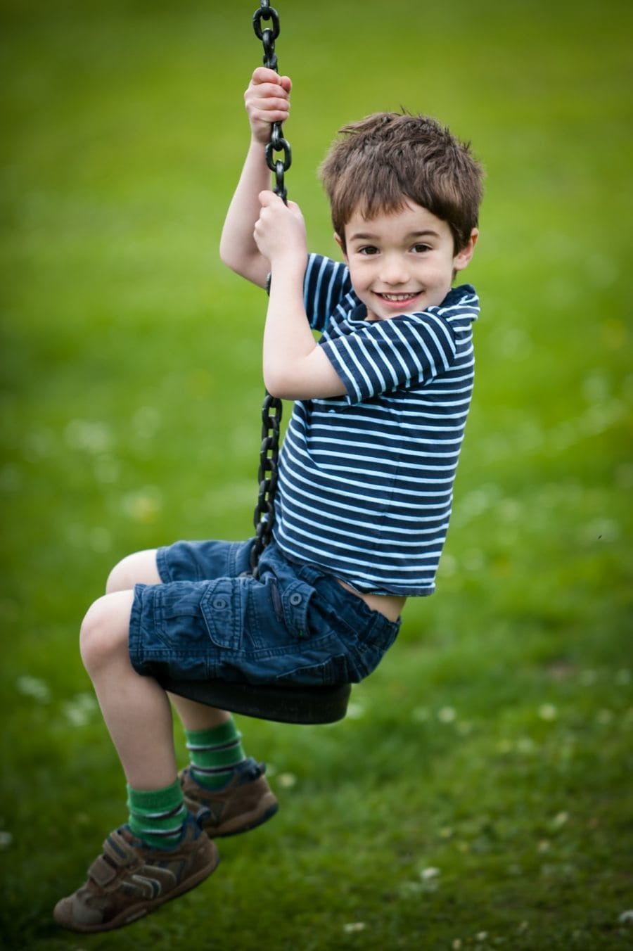 Boy sits smiling on a zip line at a Kemsing playground