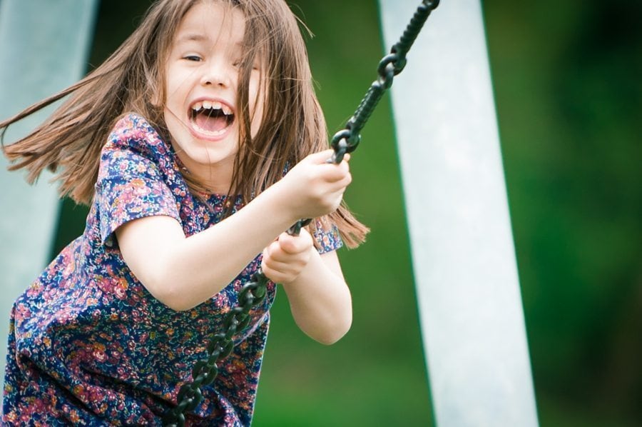 Little girl laughs as she sits on the zip line