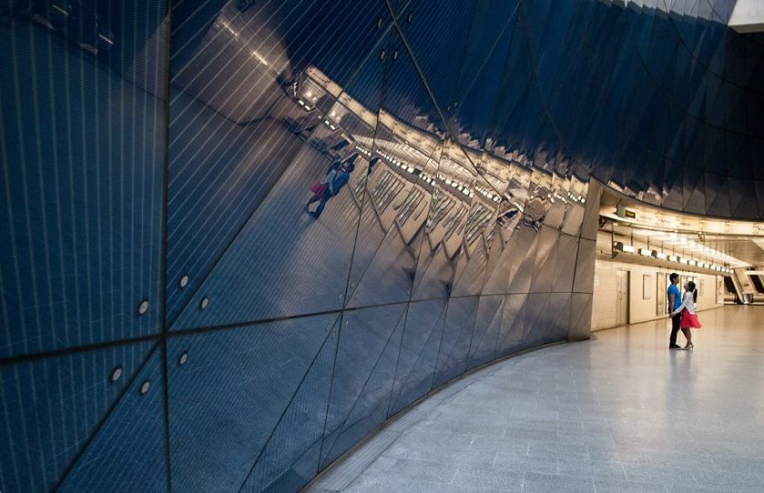 Couple hugging & laughing reflected in Southwark station wall