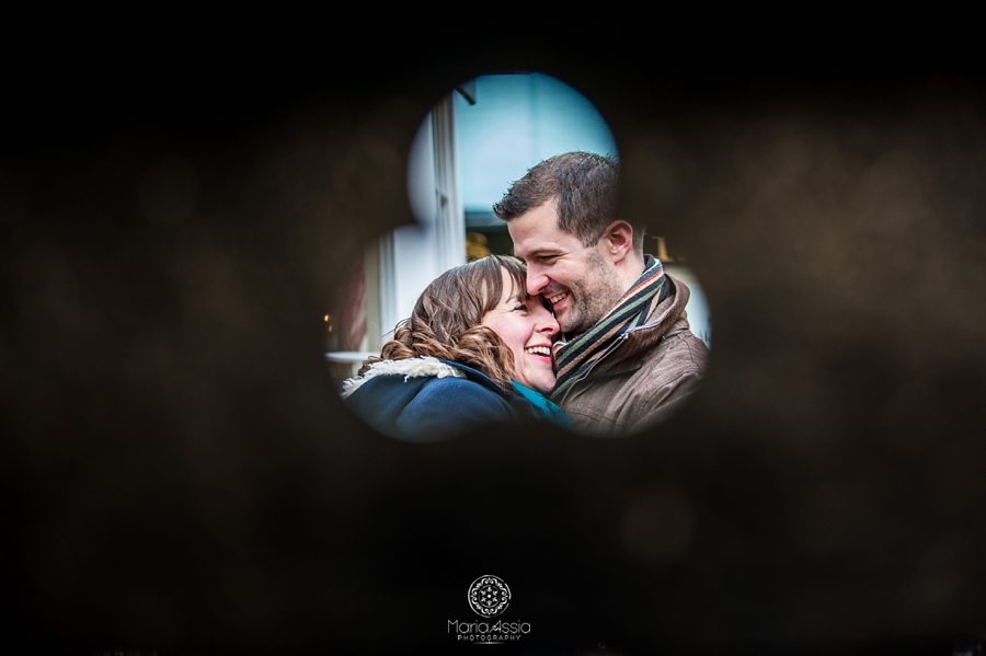 Engaged couple hugging visible through hole in the wall