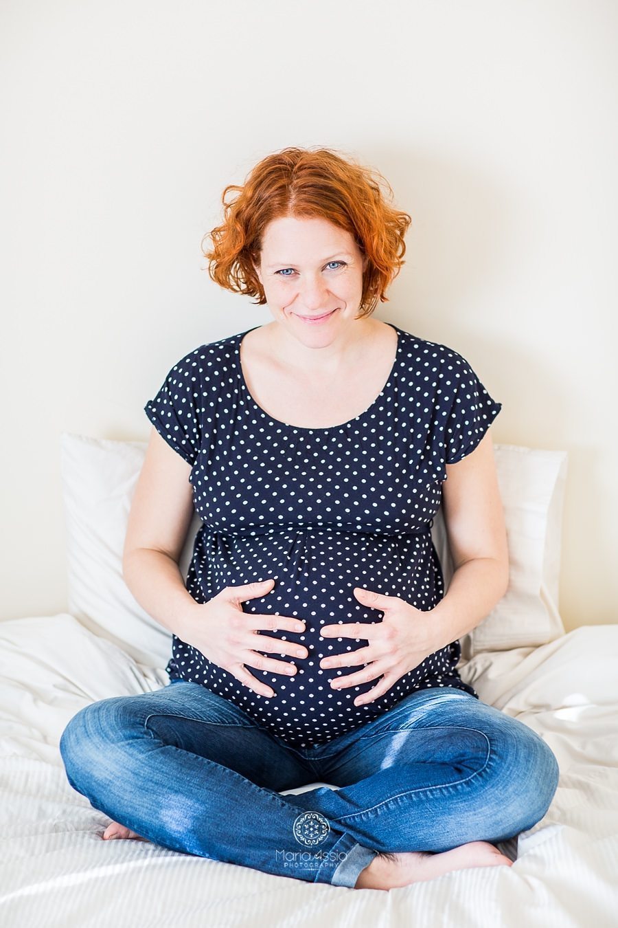 Smiling pregnant girl sitting on the bed