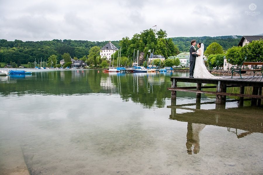 Bride and groom stand on the pier at Mattsee Austria