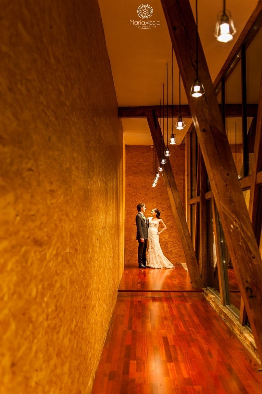 Bride and Groom stand together at the end of a red hallway