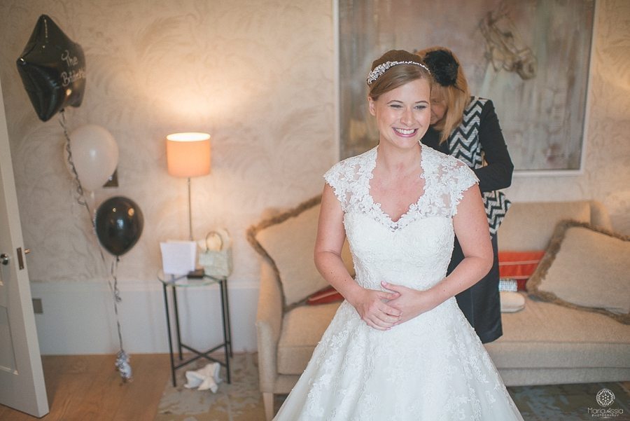 Happy Bride getting into her wedding dress in the bridal suite at Coworth Park