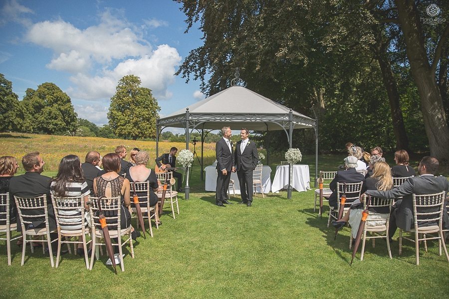 Groom talking to his best man and guests in the meadow at Coworth Park summer wedding