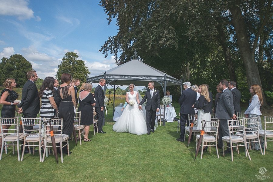 Bride and groom walking through the wildflower meadow at Coworth Park