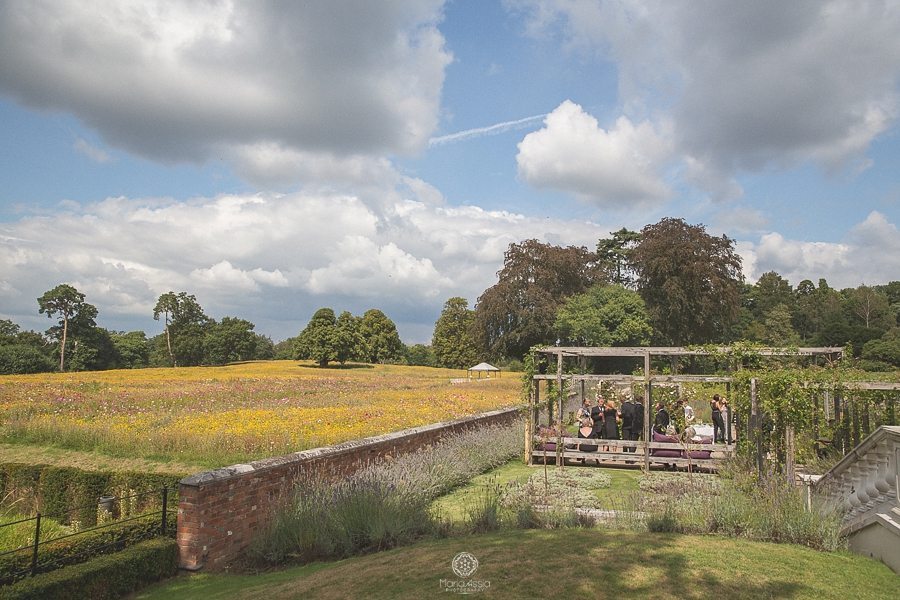 Wedding guests chatting in the sunken garden at Coworth Park