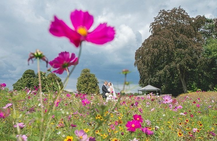 Bride and groom standing in the Coworth Park meadow