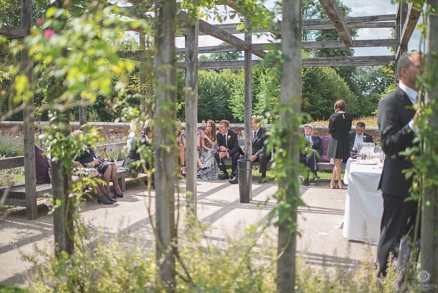 Wedding guests chatting in the sunken garden at Coworth Park