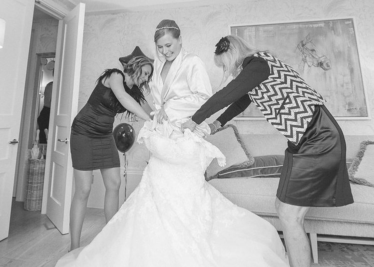 Black and white photo of bride climbing into her dress