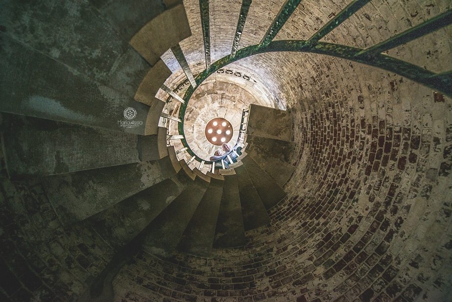 Man and woman standing at the top of a winding staircase at Hurst Castle, Creative engagement photos