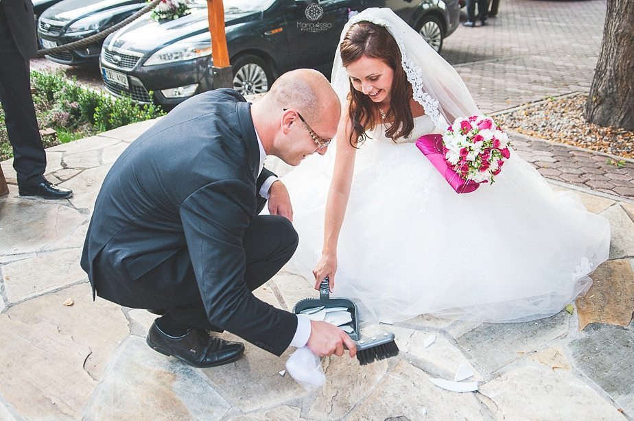 Bride and groom sweeping up shards at a Prague star summer palace wedding.jpg