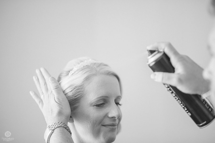 The hands of the hair stylist apply the finishing touches to the bride's hair