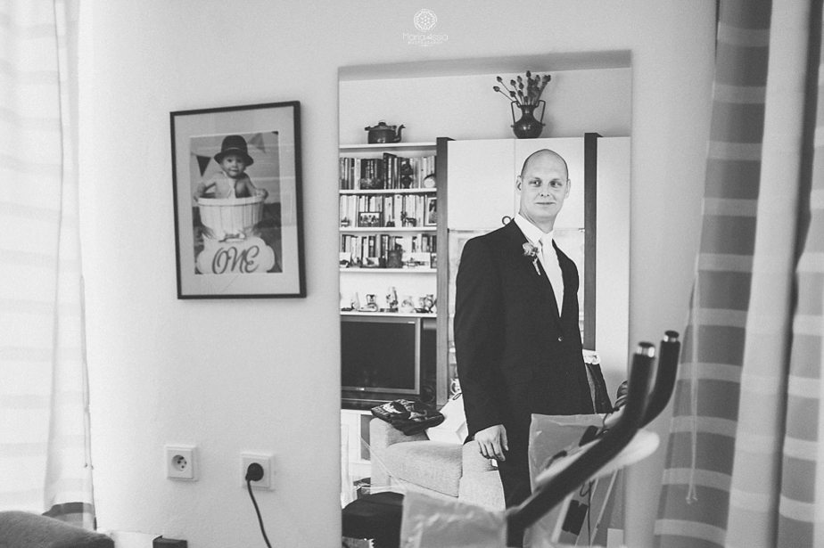 Groom looking at himself in the mirror before his Prague Star Summer Palace Wedding.jpg