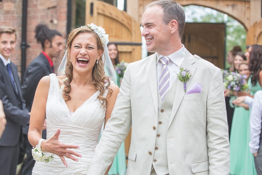 Bride and groom laughing widely down the aisle