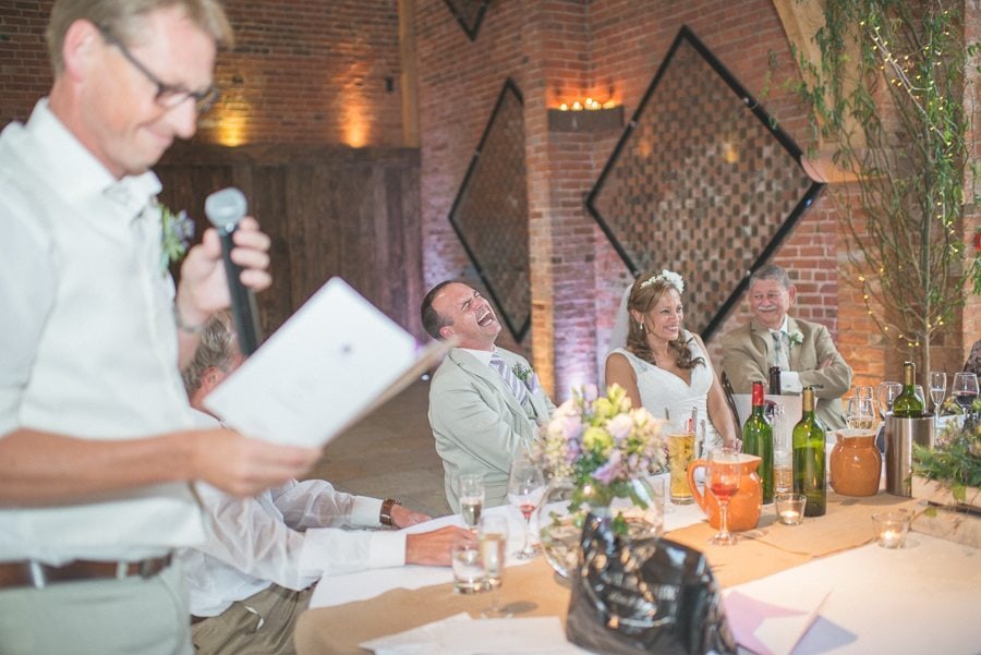 Bride and groom laughing loud during the best man's speech