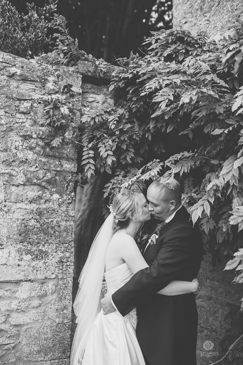 Bride and groom kissing below wisteria leaves at Caswell House purple themed autumn wedding