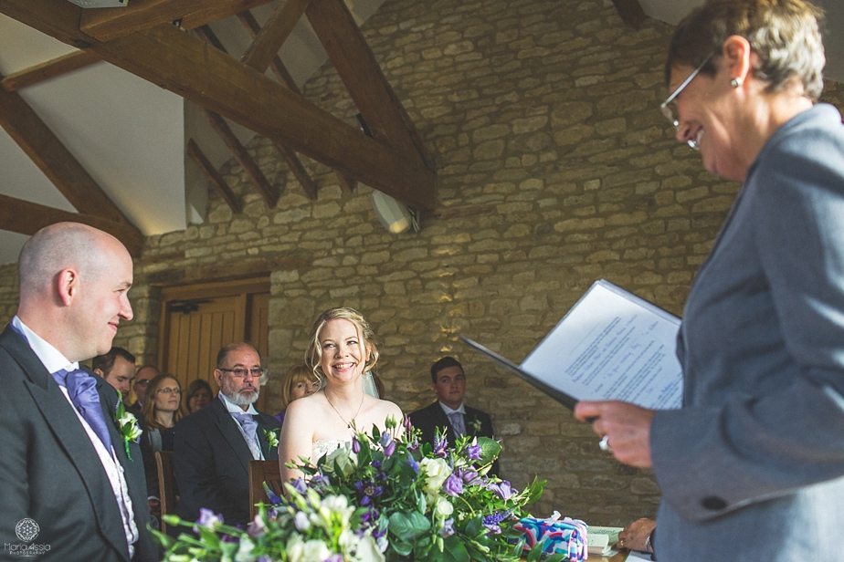 Bride and groom smile at each other while their registrar marries them at their Purple Themed Autumn Wedding