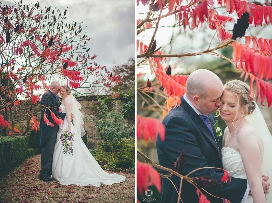 Caswell House Purple Themed autumn Wedding Bride and groom standing in red autumn foliage leaves