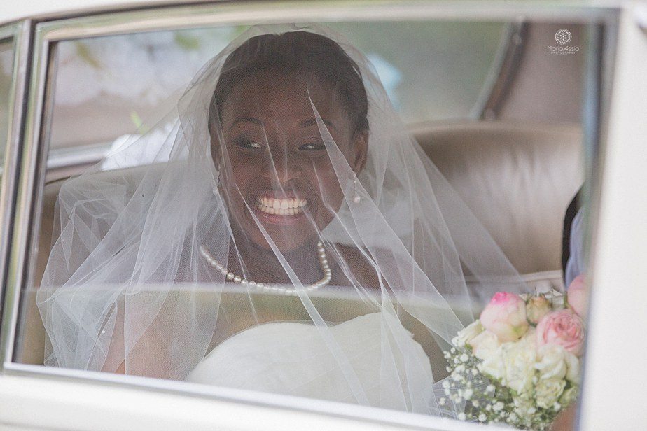 Colourful Ethnic Wedding Bride smiling at her guests from her classic car