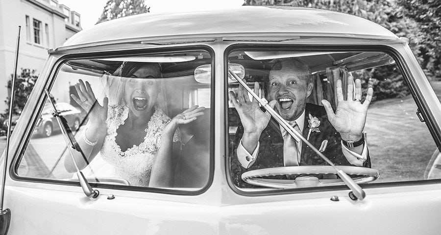 Bride and Groom waving hello from a VW campervan