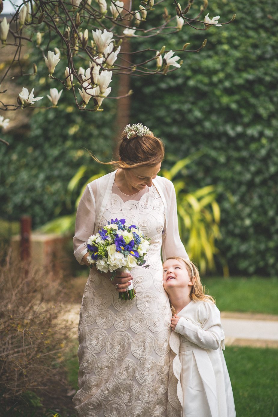 A bride smiling at her daughter under a magnolia tree at Warren House