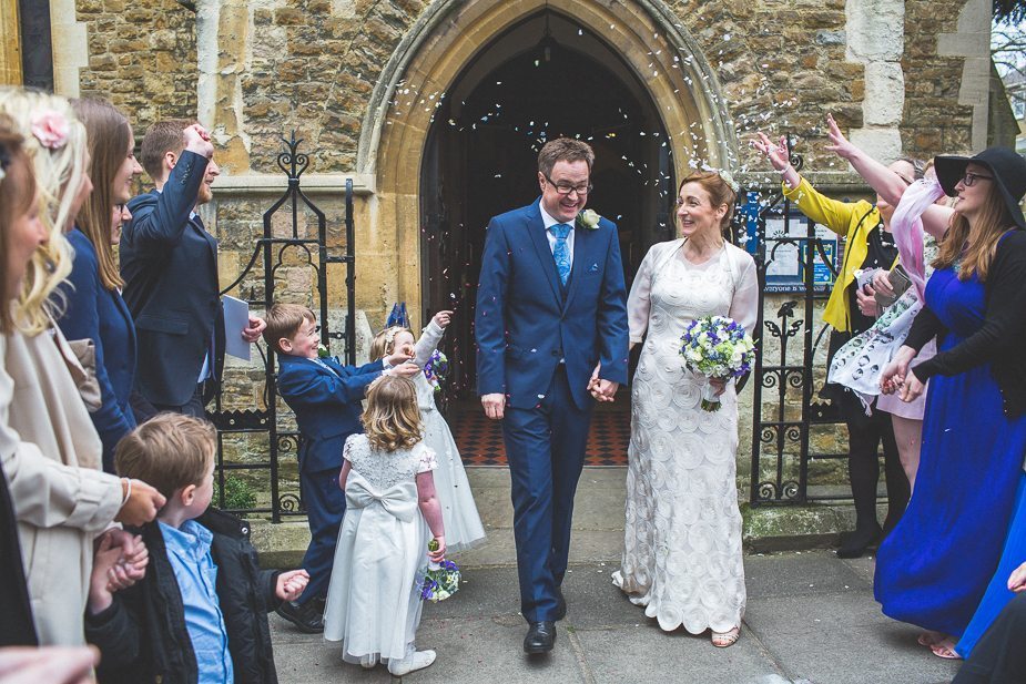 A bride and groom walking out into a confetti shower