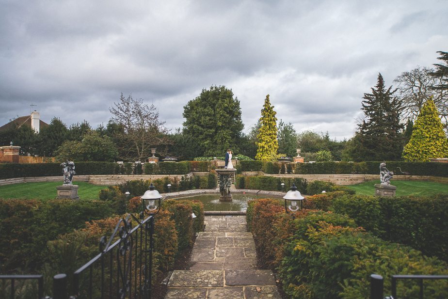 A bride and groom standing by the fountain at Warren House