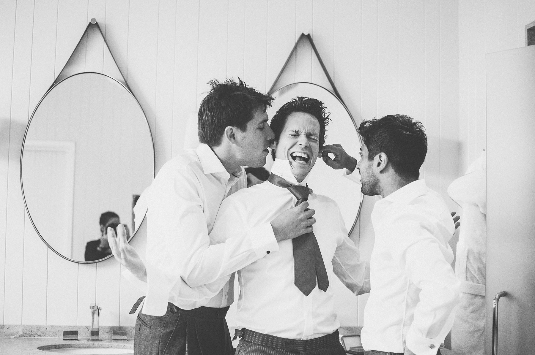 Groomsmen tickling the groom at coworth park barn stables