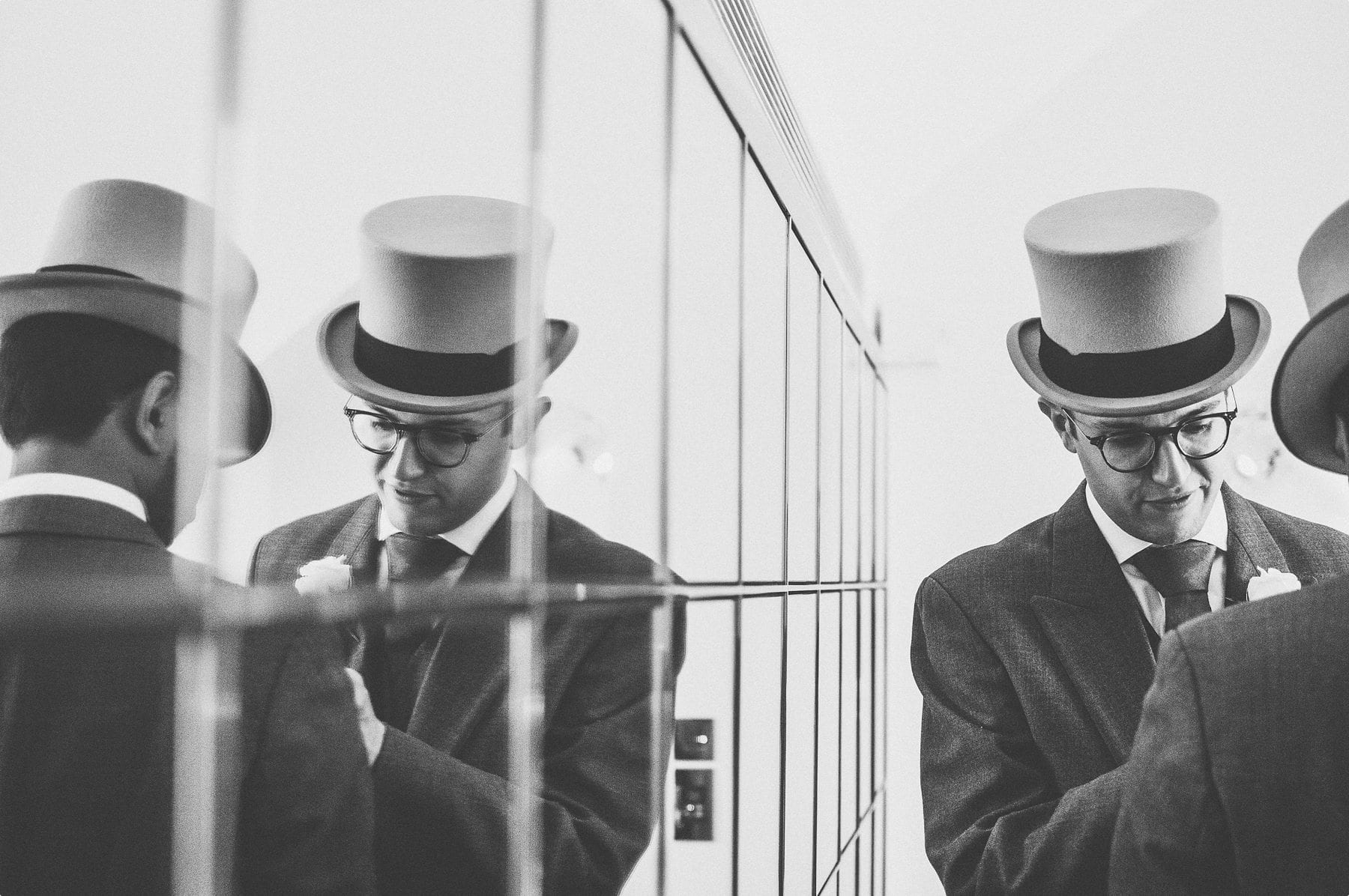 Groomsmen getting ready and their reflection in the mirror at Coworth Park barn stables