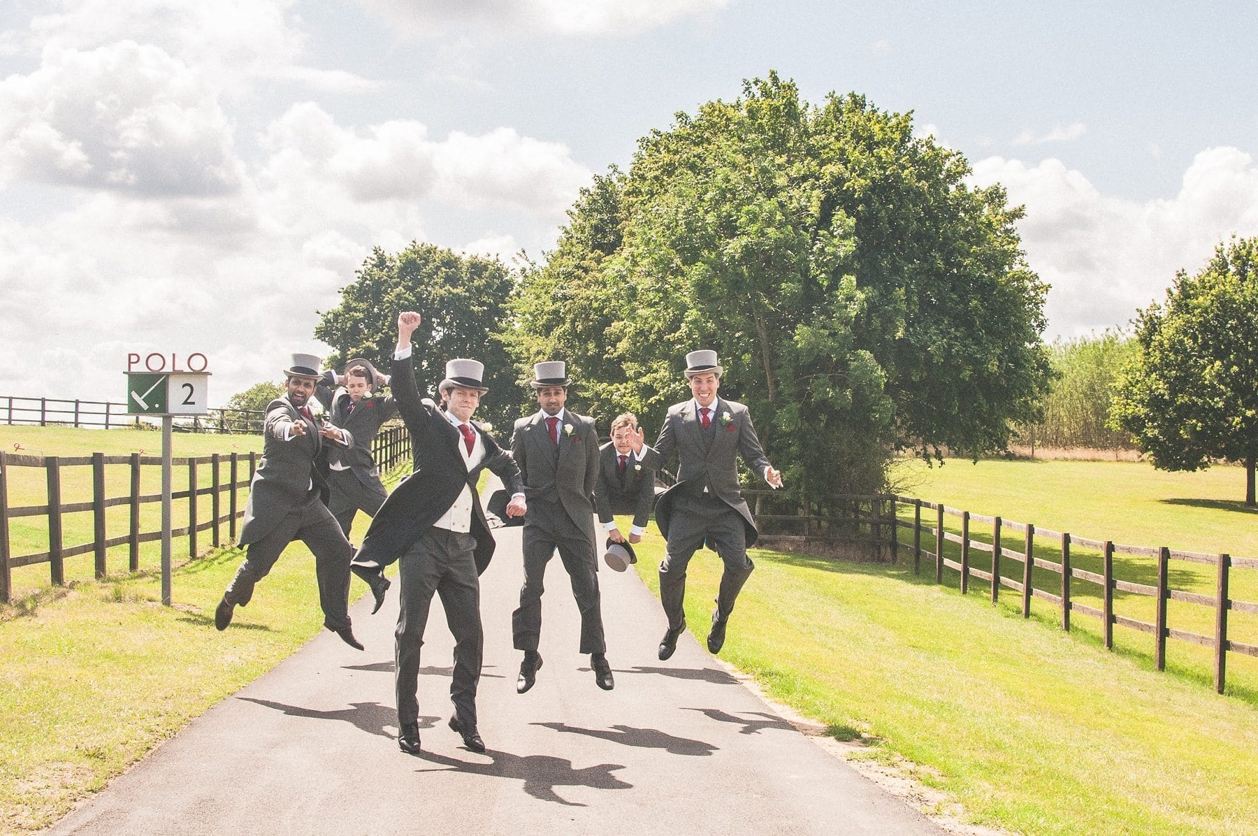 Groom and groomsmen jumping at Coworth Park summer wedding grounds