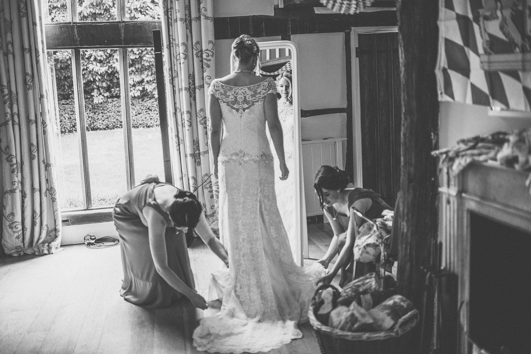 Bridesmaids straightening out the bride's dress at Coworth Park barn's Dower House