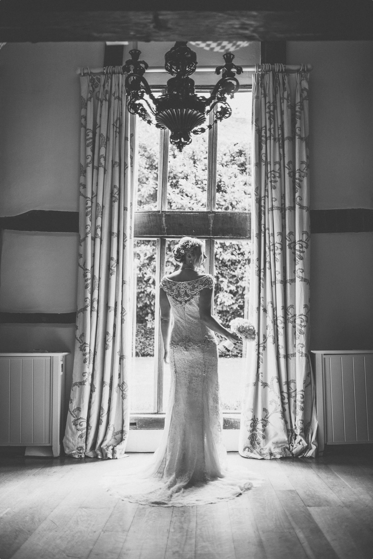 Bride standing in the Dower House window ready for her Coworth Park barn summer wedding