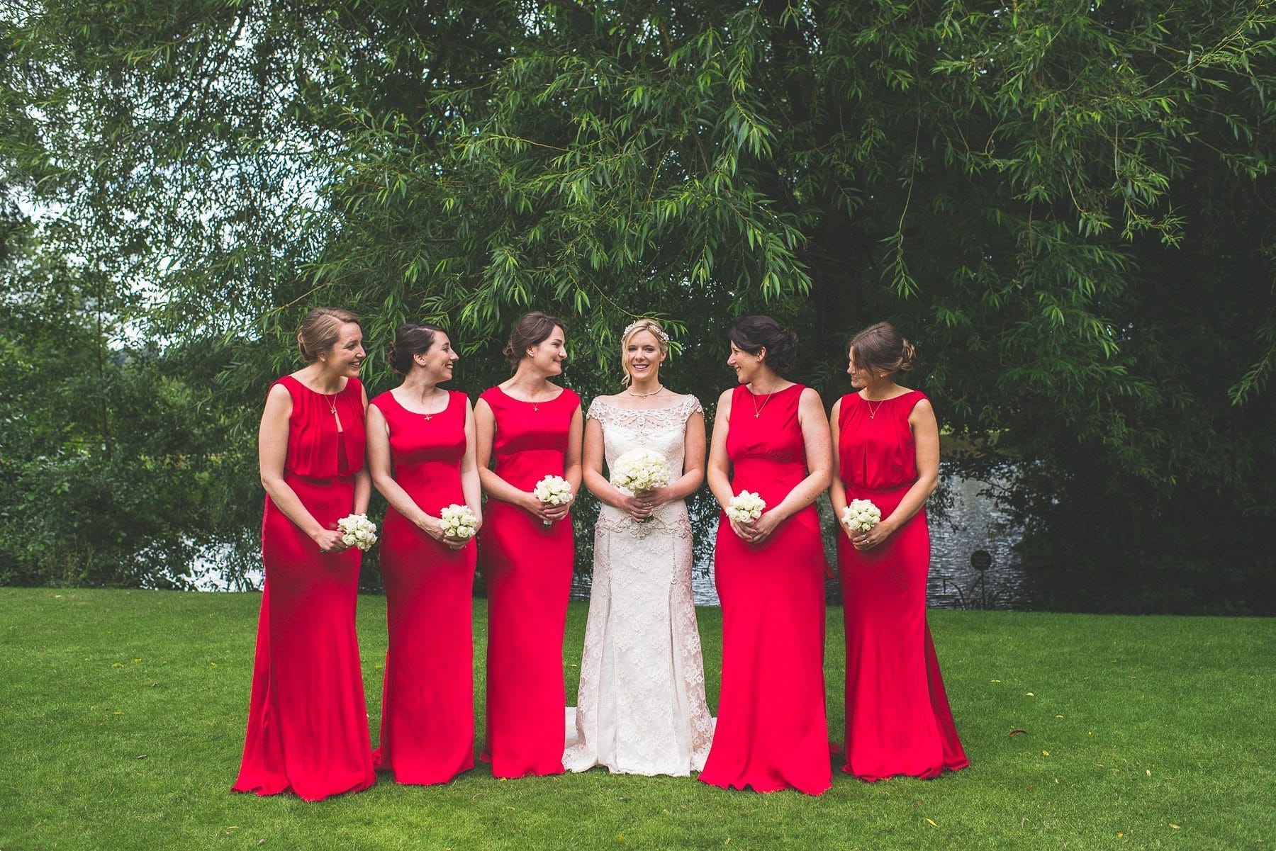 Coworth Park Barn summer wedding photography of the Bride and her bridesmaids wearing red bridesmaids dresses