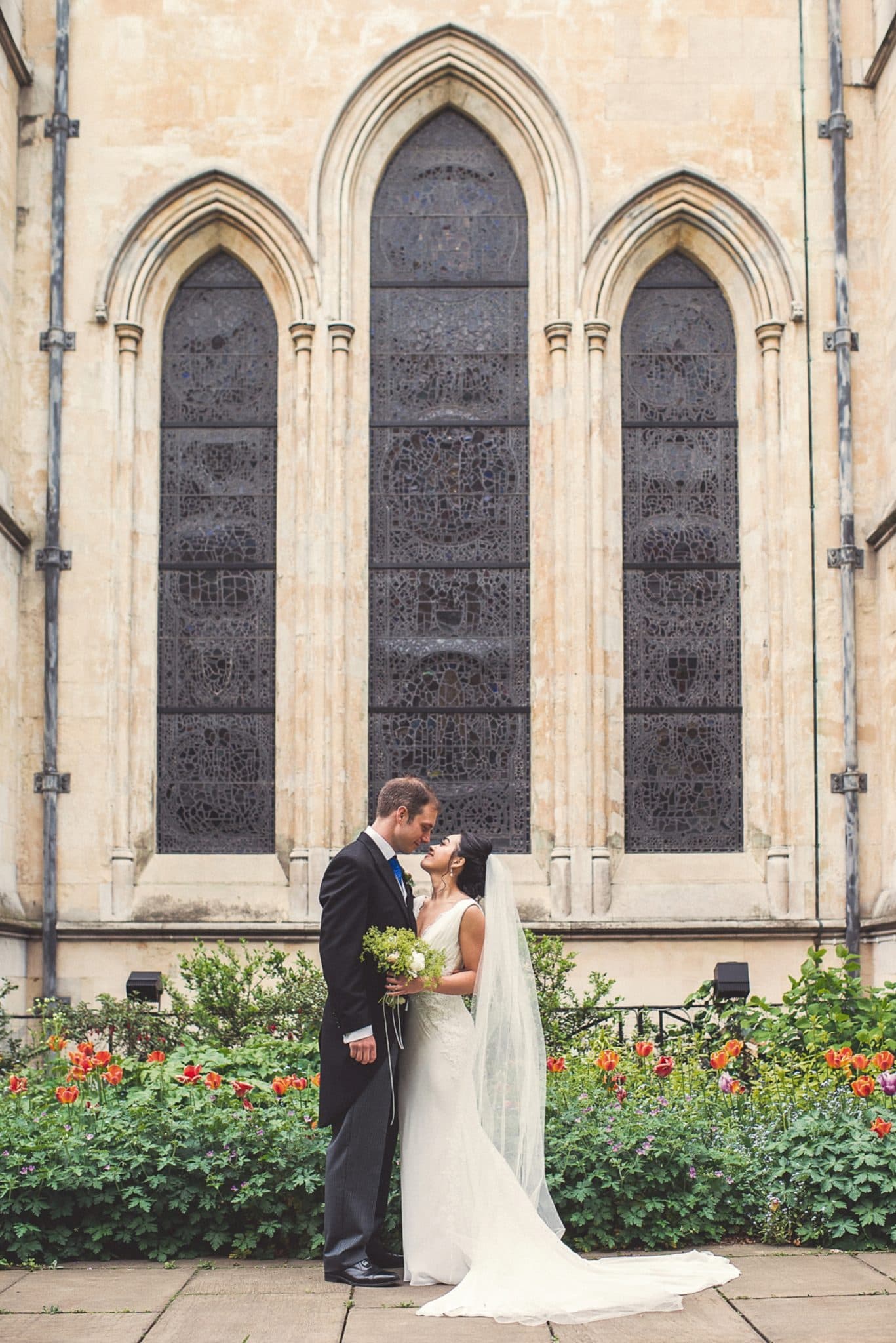 Bride and Groom stand in front of the stained glass windows of Temple Church in London