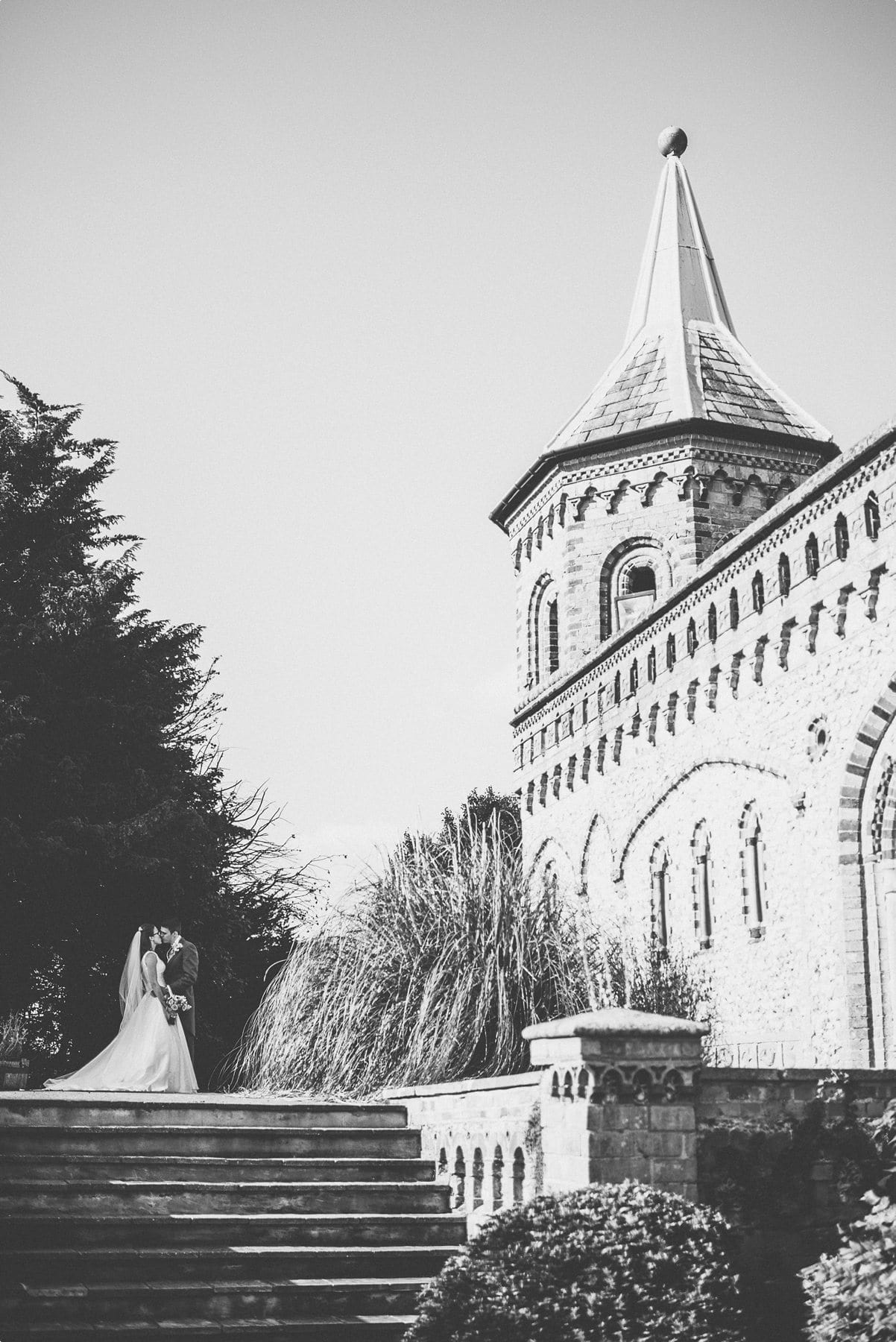 Natural wedding portrait of the bride and groom kissing in the shade of the Horsley Tower