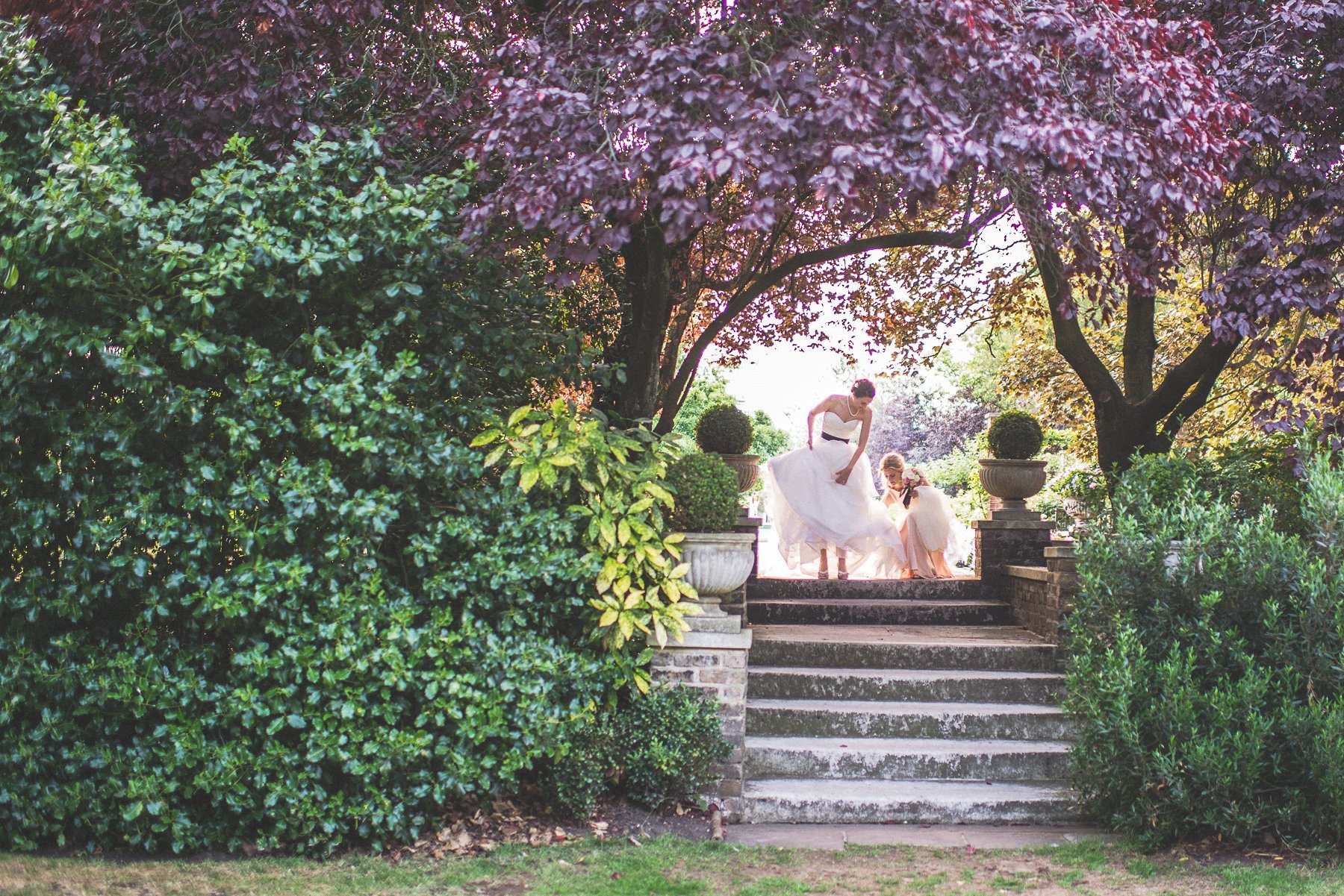 Bride walking down the stairs in bright sunshine and colourful leaves at the Hurlingham Club glamorous music themed Chelsea wedding in London