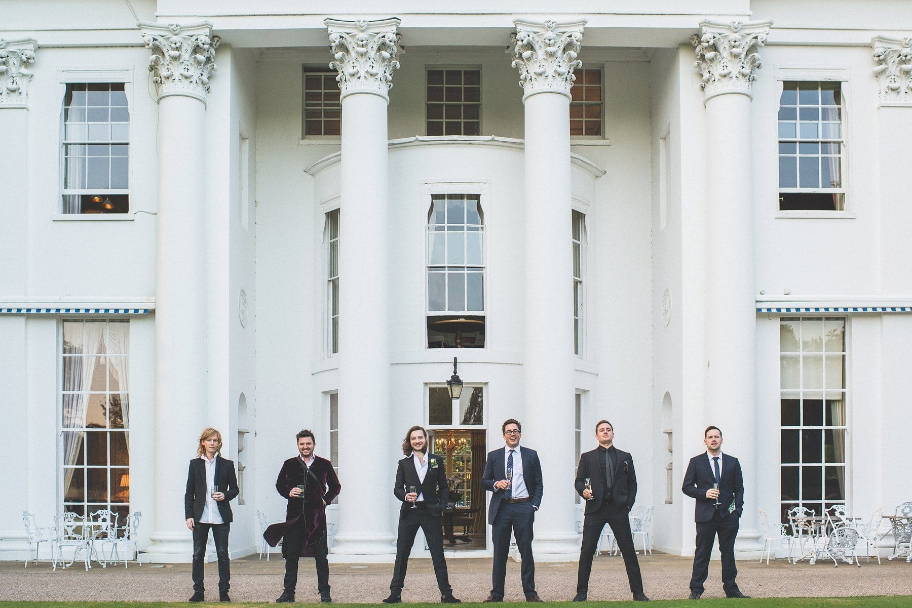 Groom and groomsmen standing in front of the white marble columns at the Hurlingham Club wedding