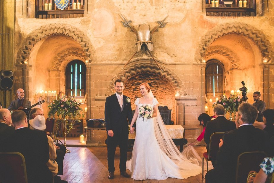 Bride and Groom walking out of their candle lit Hedingham Castle Wedding ceremony