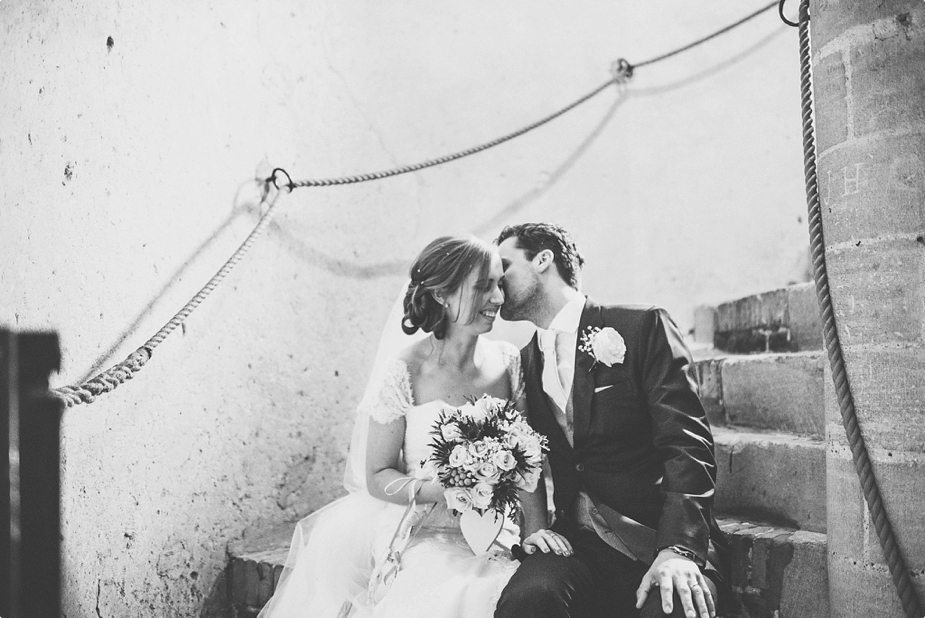 Bride and Groom sitting and kissing on the stairs at Hedingham Castle