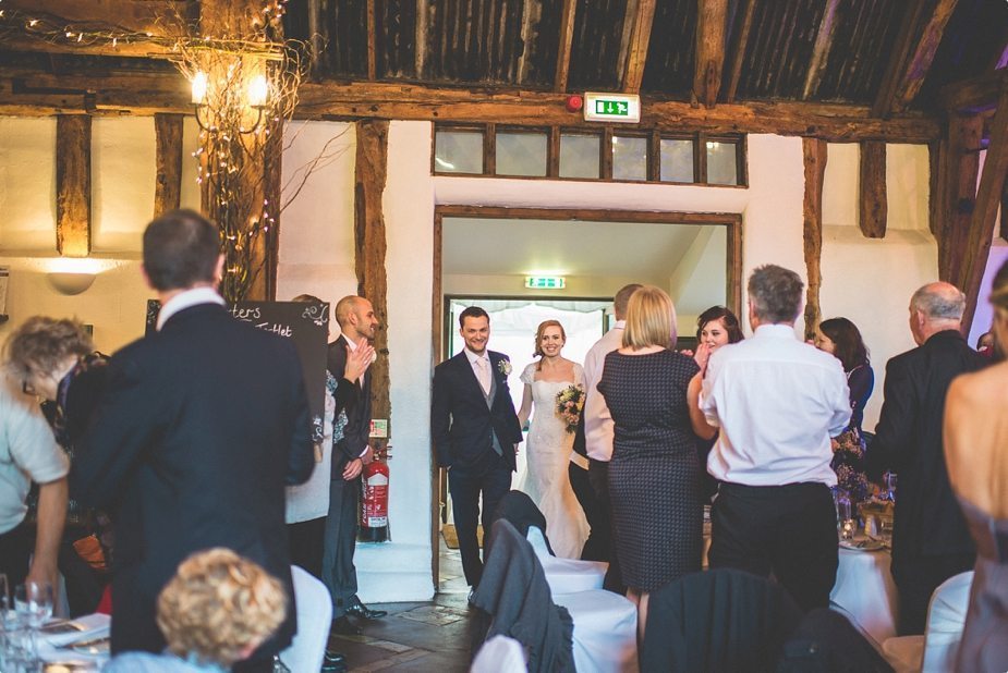 Bride and groom walking into the main hall at their Smeetham Hall Barn rustic rainy wedding