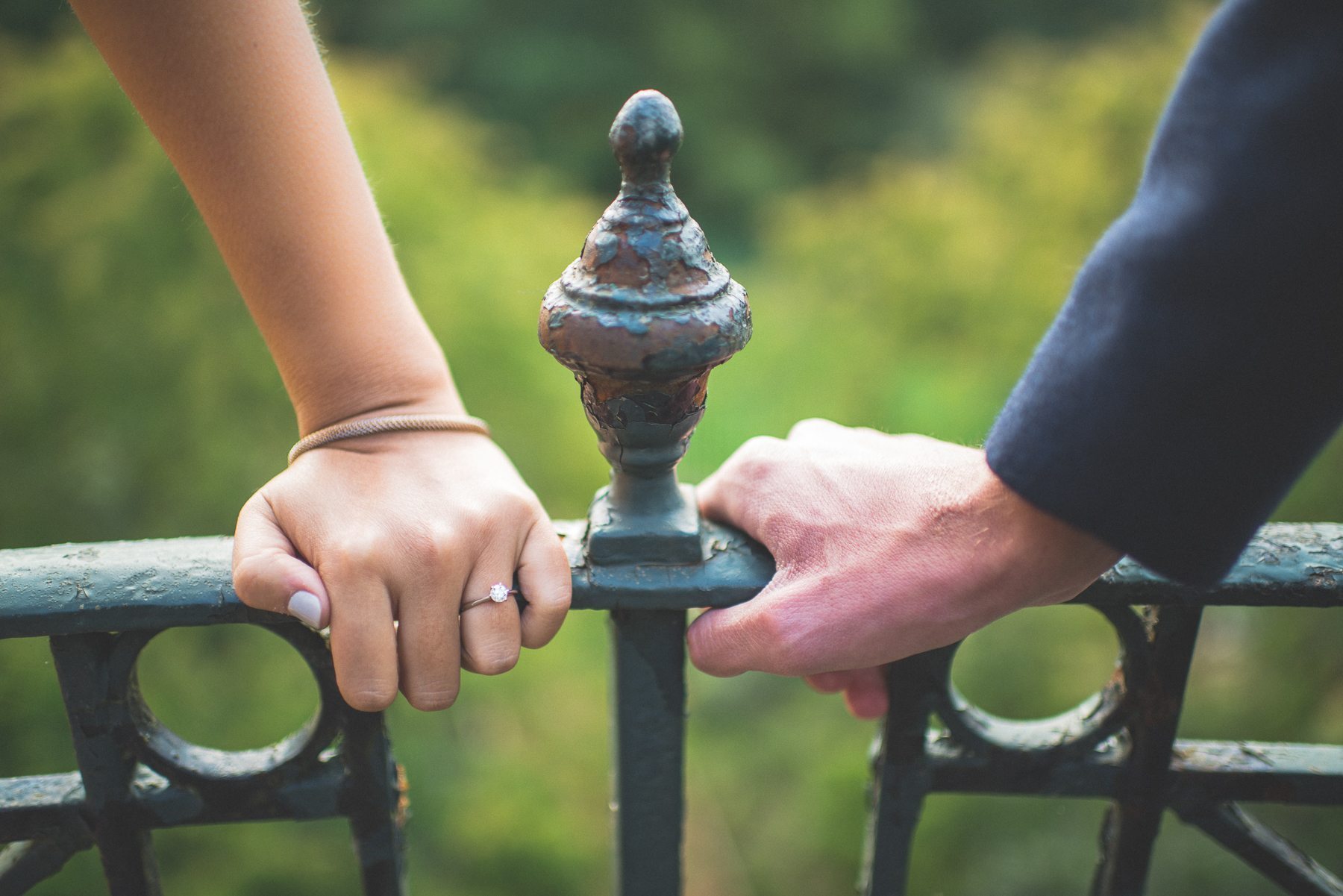 Engaged couple's hands holding on closely to a railing