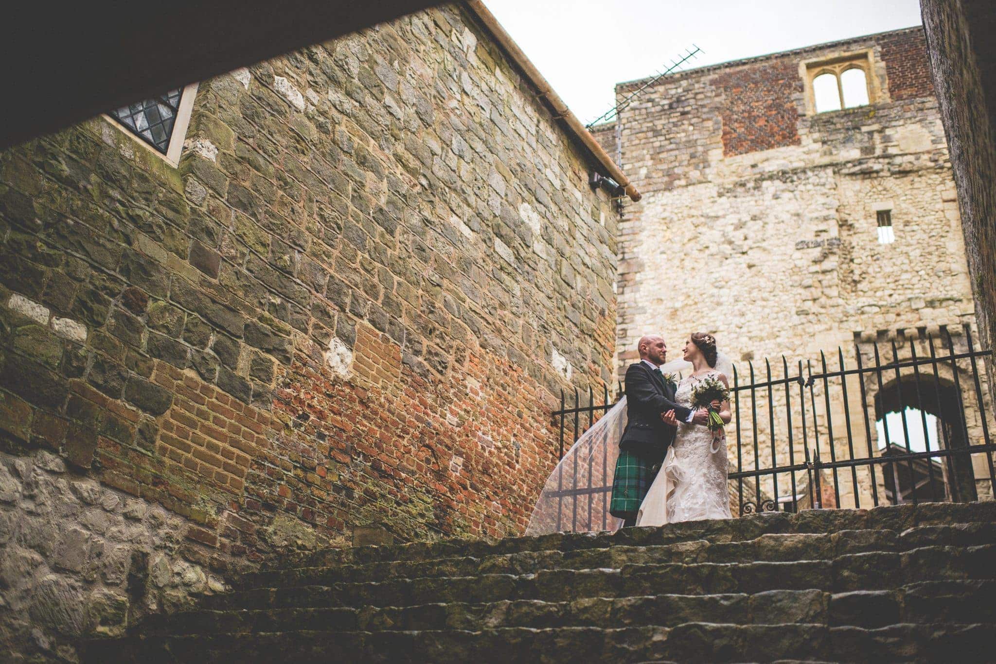 Bride and Groom laugh at each other at the steps of the Keep at Farnham Castles