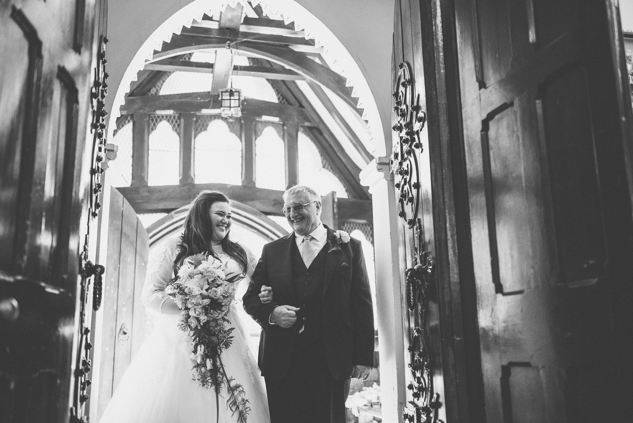 Bride and her dad smile at each other at the entrance to the church