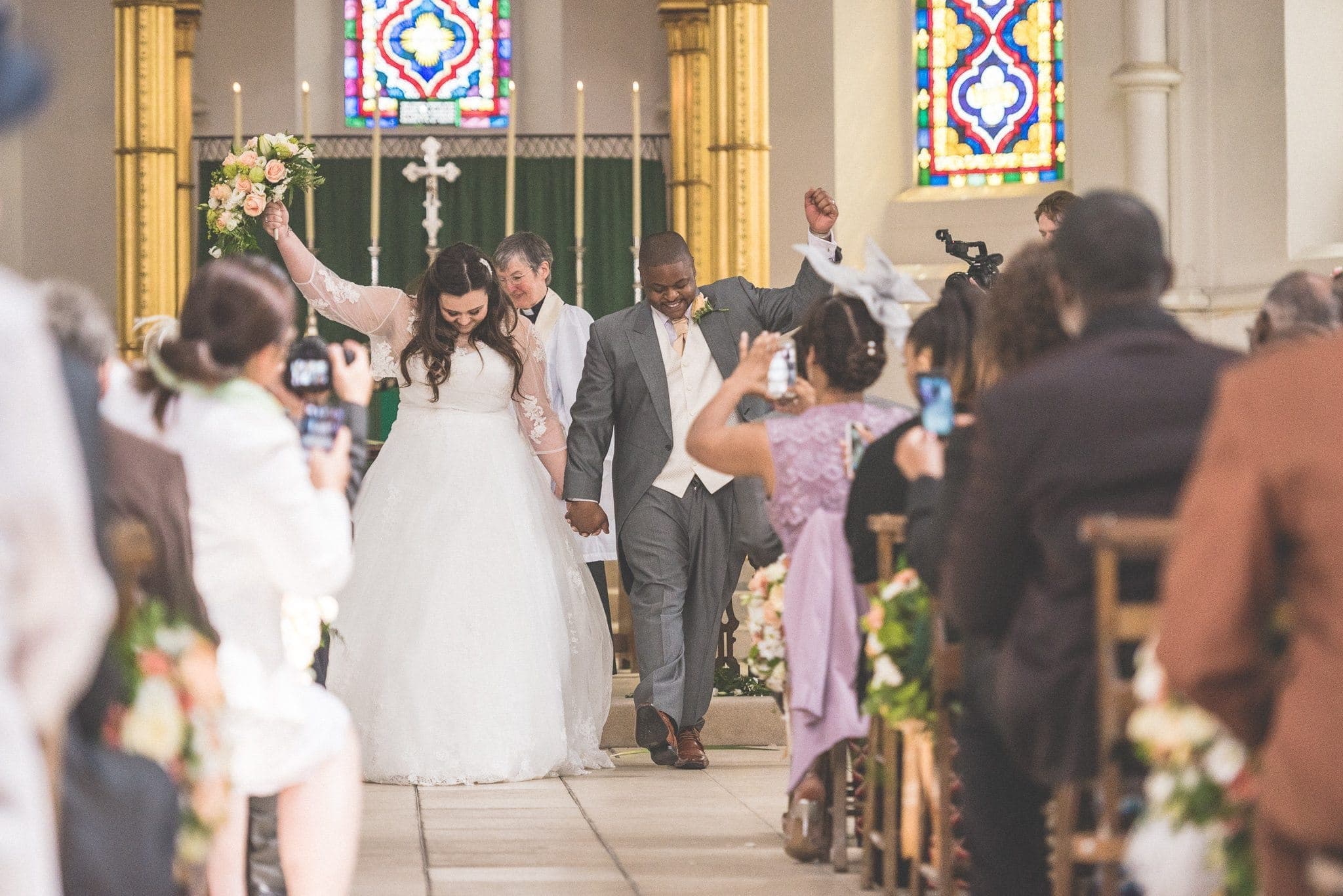 Bride and groom cheering as they walk down the aisle