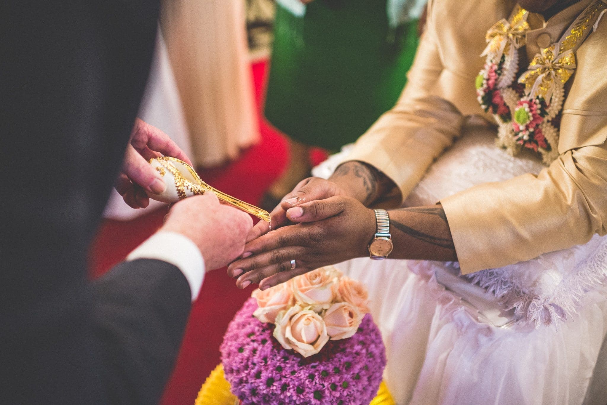 Water pouring over the grooms hands at his Thai water blessing ceremony