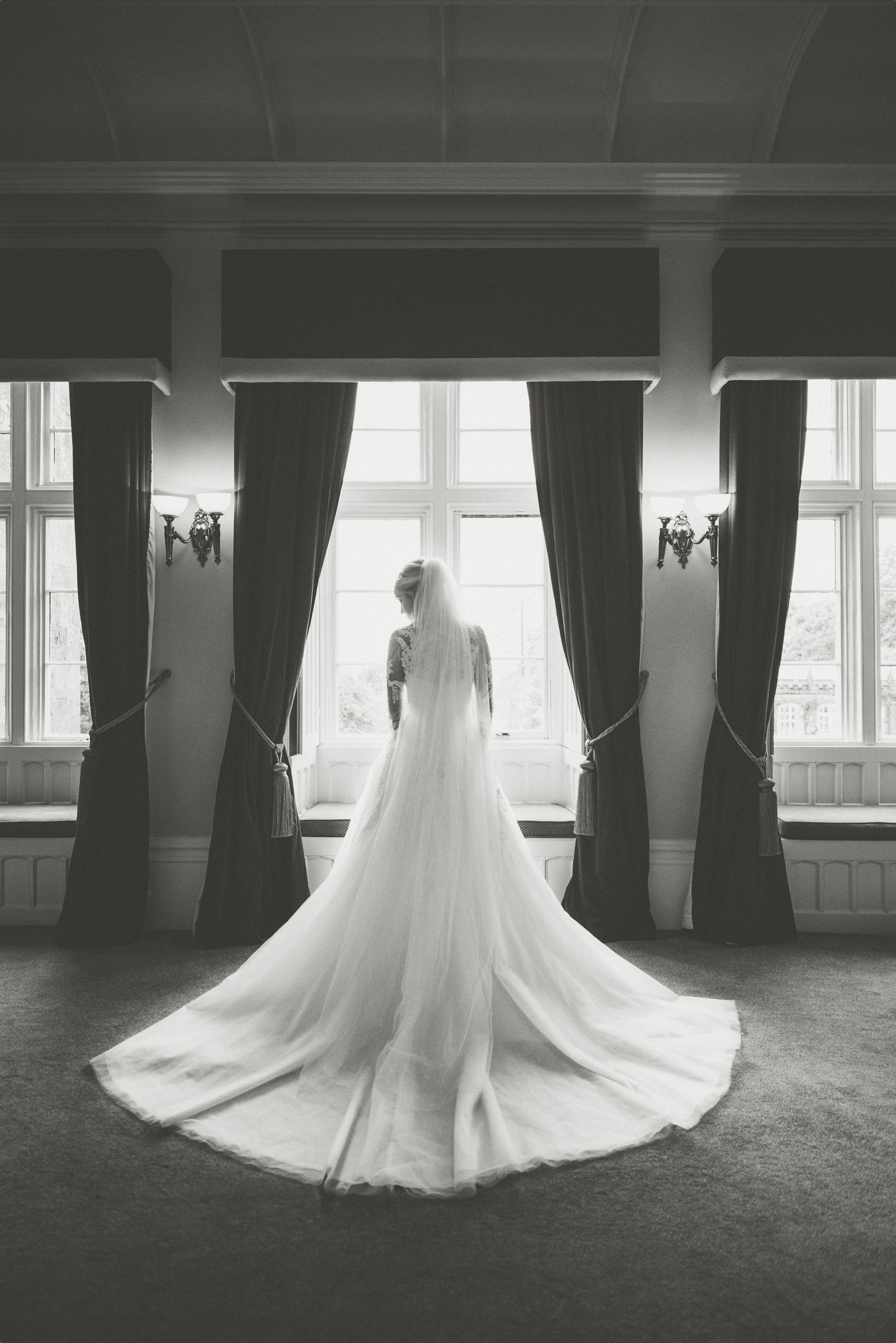 Bride standing in the window at her St Audries Park Sophisticated Rainy Wedding