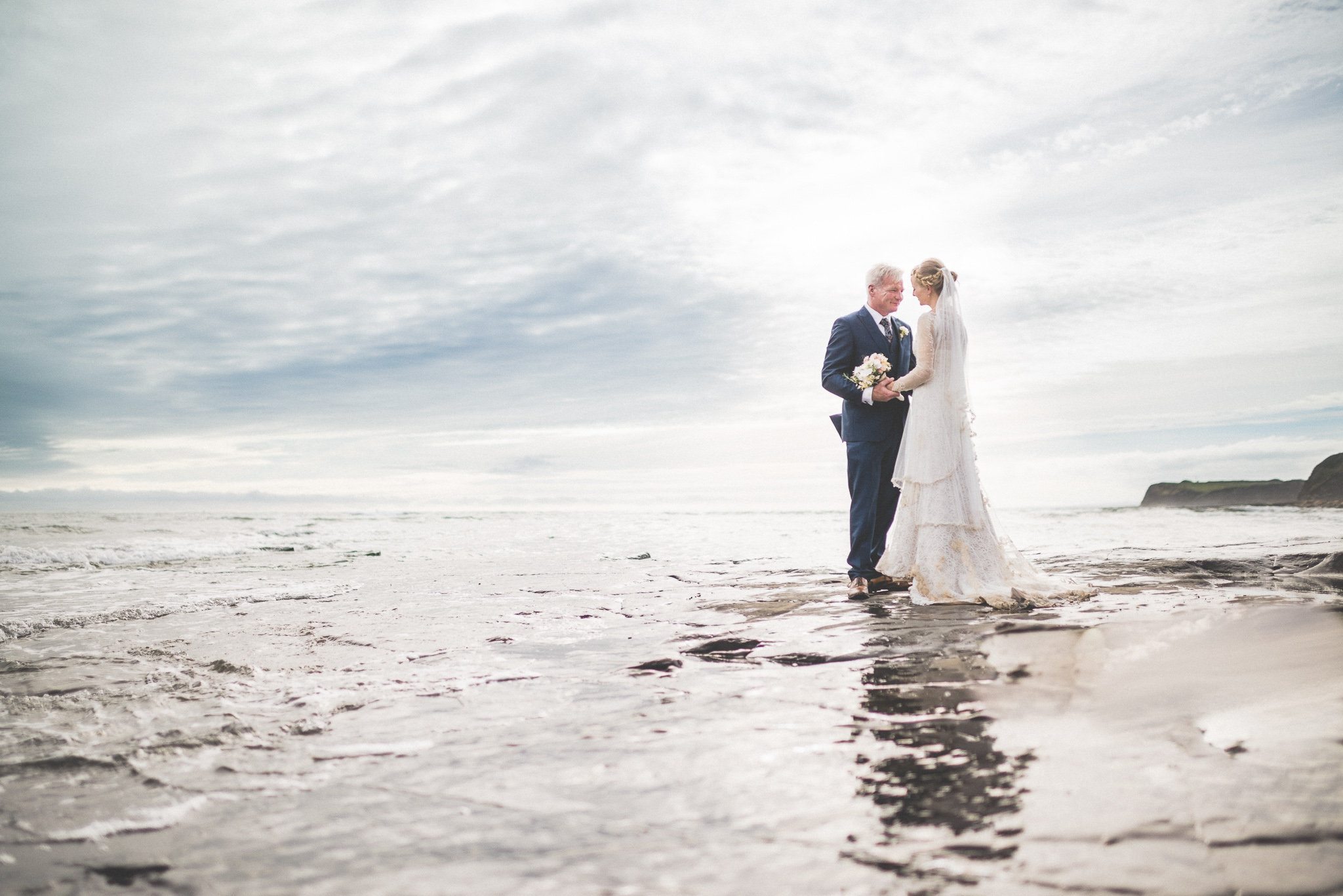 Smedmore House Bride and Groom stand in the waves at Kimmeridge Bay